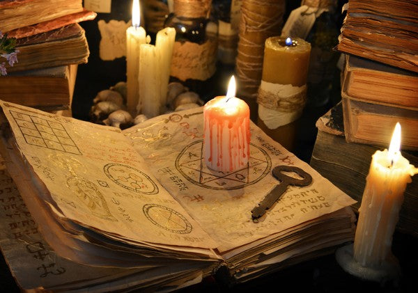 A low magic ritual happening with a candle burning on an open book with symbols in it. Surrounded by other cunning magic relics.