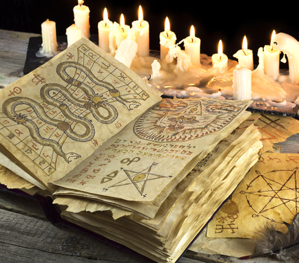 Candles surrounding an ancient Grimoire spellbook.
