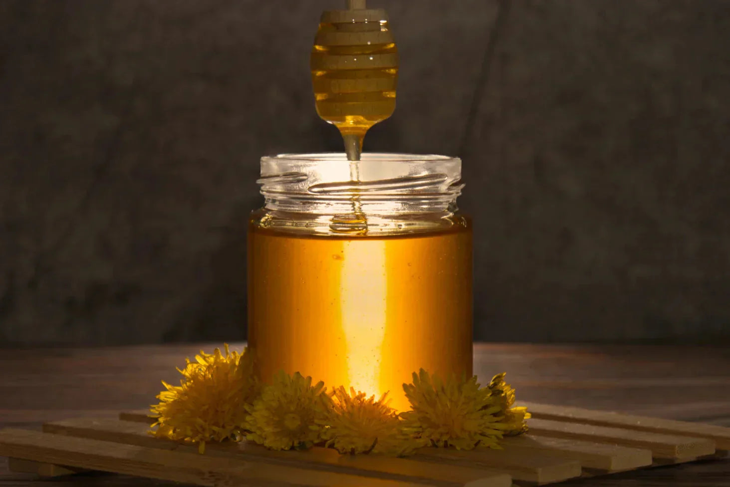 A backlit jar of honey with dandelions, perfect for a honey jar love spell.
