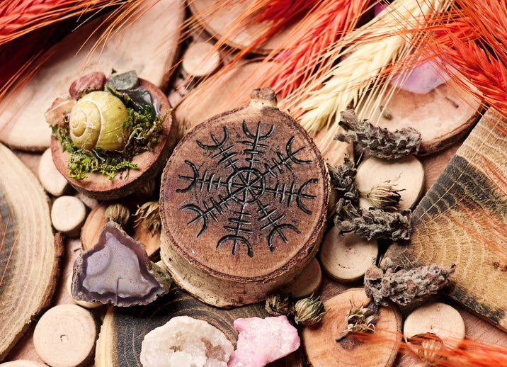 What are sigils and how do you use them? A sigil burned into a slice of a tree stump with crystals, herbs, and wheat around it.