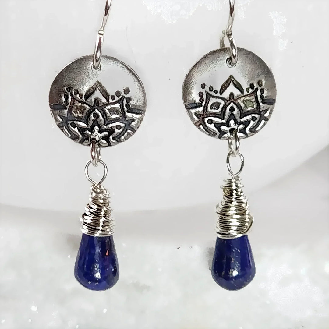Close-up of handcrafted lapis teardrop earrings with lotus fine silver discs.