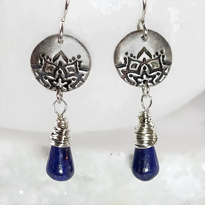 Close-up of handcrafted lapis teardrop earrings with lotus fine silver discs.