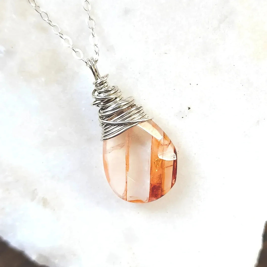 Sterling silver wire-wrapped necklace with a polished red quartz crystal pendant on a silver chain.