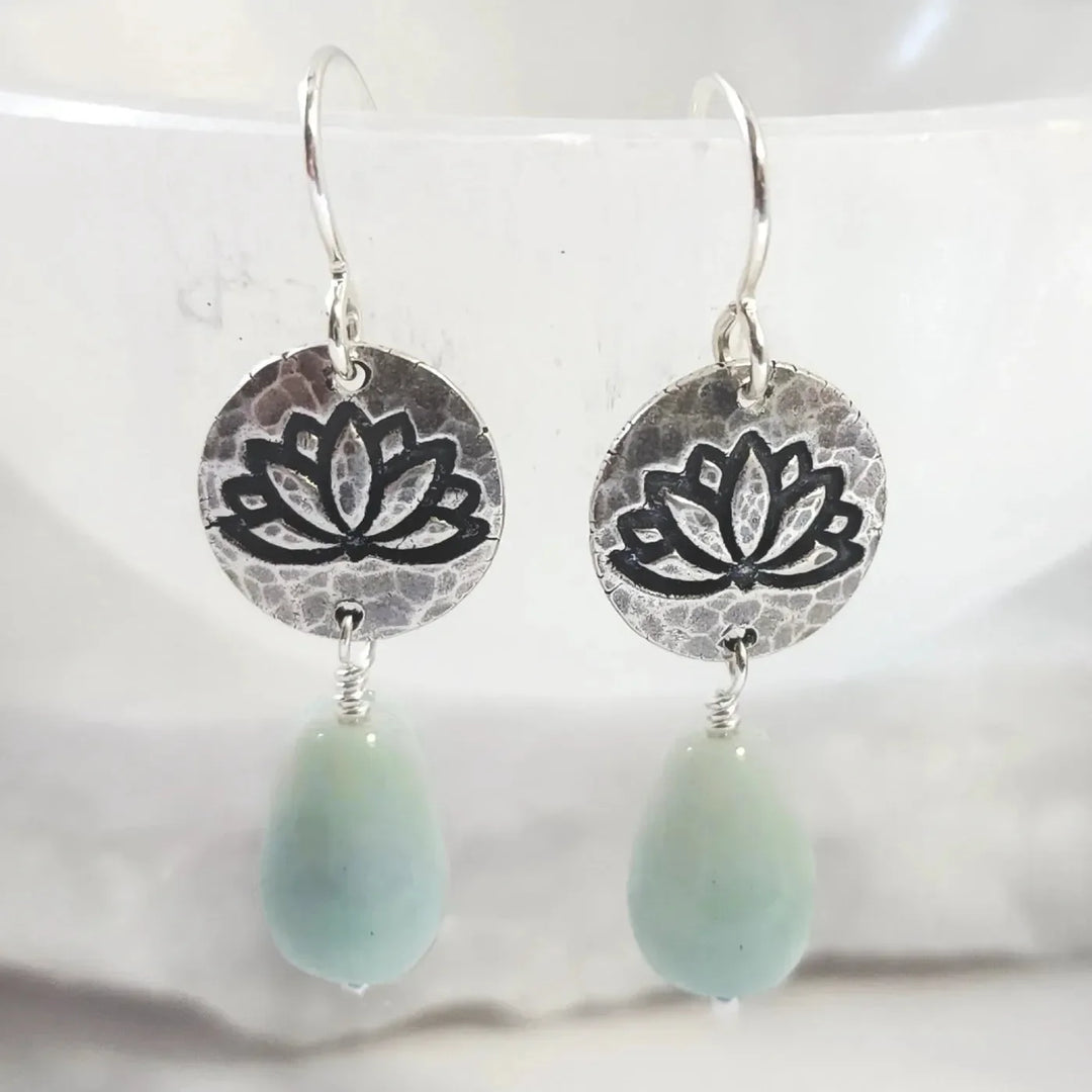 Handmade silver lotus earrings with aquamarine crystal teardrops on display bowl