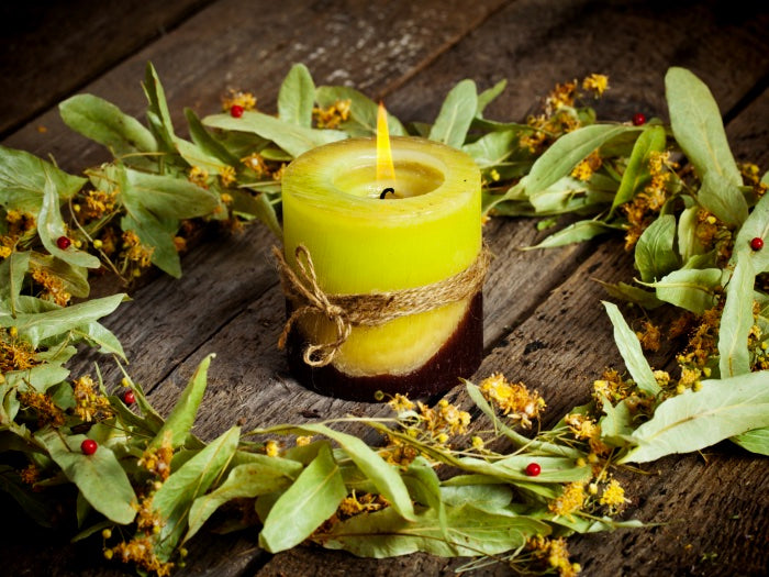 A candle surround by Linden leaves and blossoms. Read about Linden magic here.