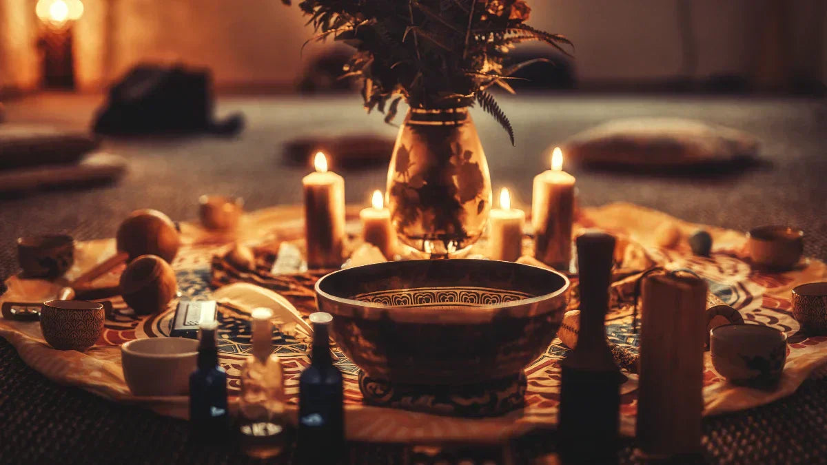 Candlelit sacred space with ritual tools, singing bowls, herbal sprays, and a central altar arranged for spiritual ceremony and meditation.