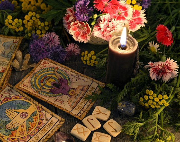 Runes, tarot cards, flowers, and a lit candle. These items and other steps may help you find your inner witch.