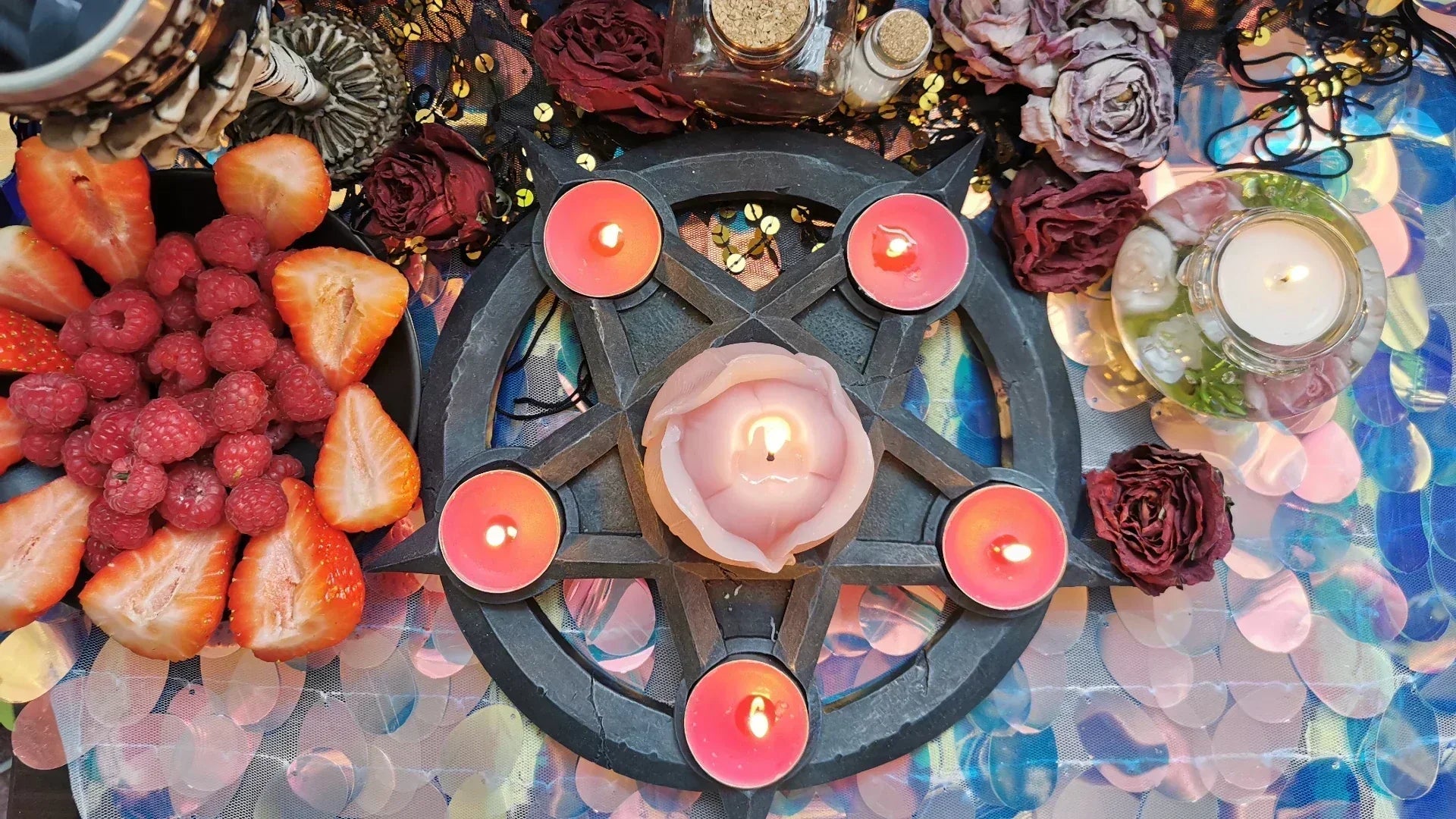Traditional love and reconciliation altar with candles, dried roses, herbs, and fresh berries.