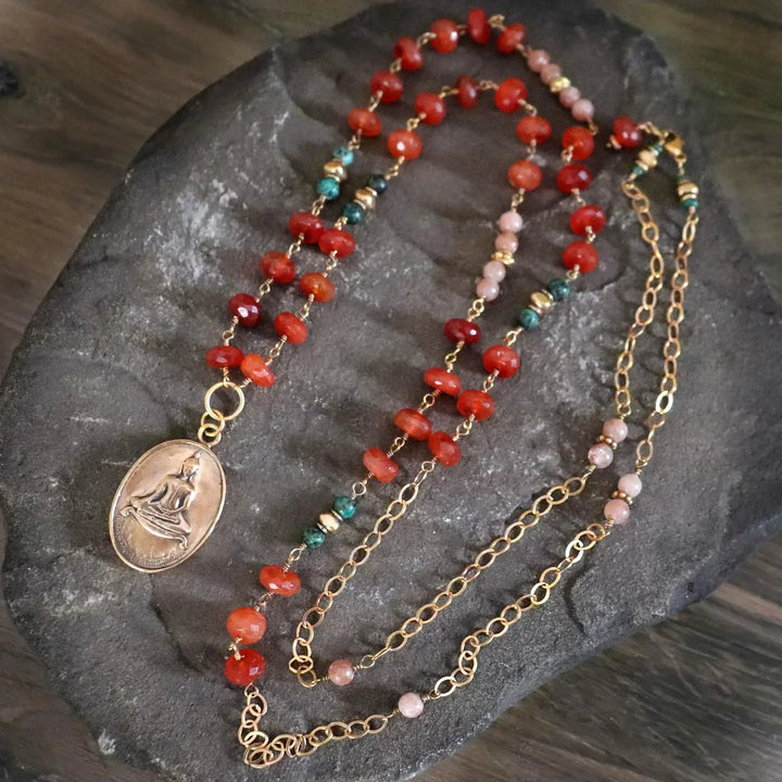Buddha Amulet Necklace with Carnelian, African Turquoise and Red Aventurine on neutral rock.
